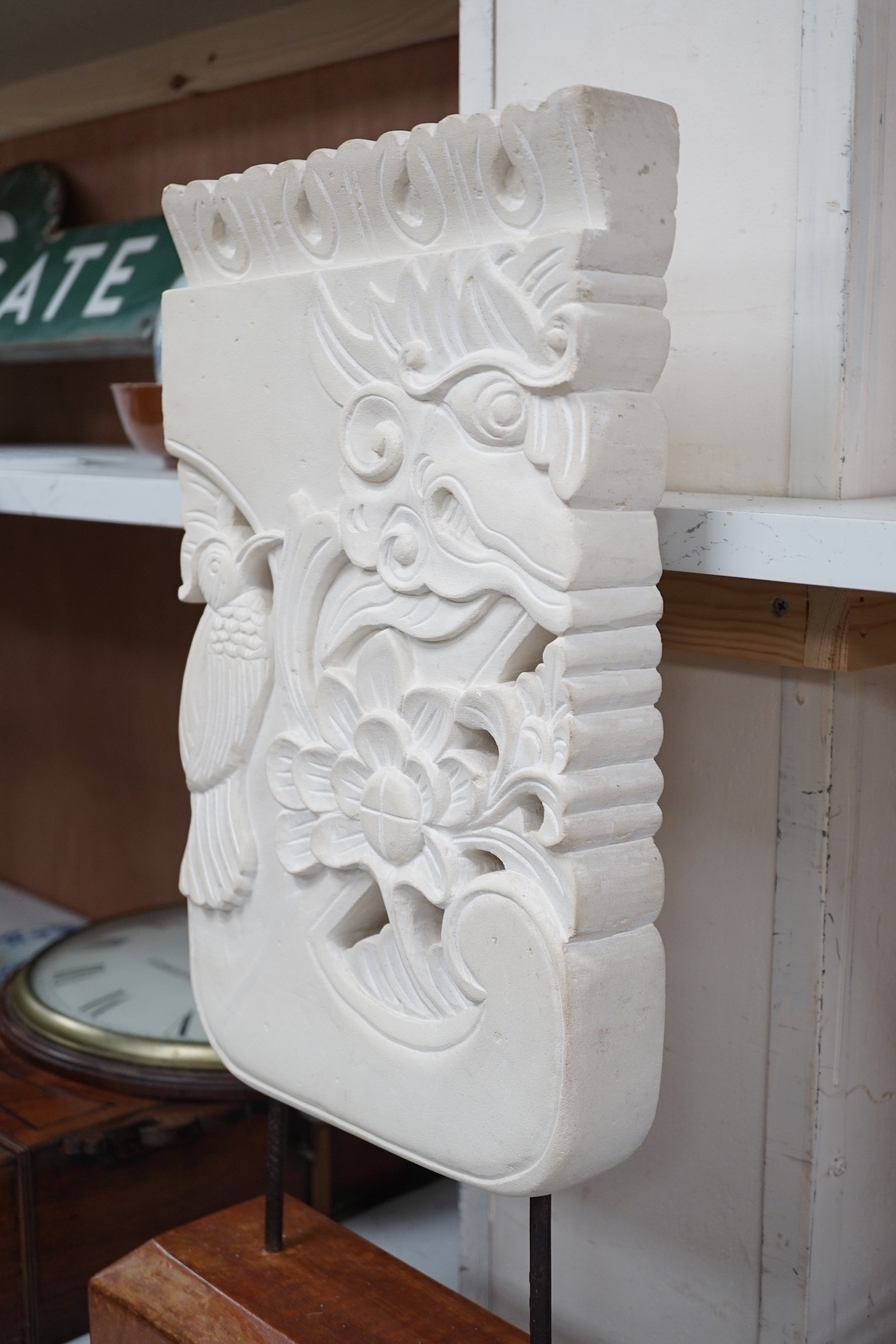 An Indonesian sandstone carving of a mask, bird and flowers on hardwood stand, 62.5cms high Height 63 cm.